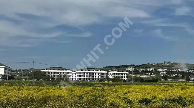 قطعة أرض بمساحة 1000 متر مربع قريبة من الطريق السريع E-5، بنسبة إعمار 25٪، تطل على الطريق وبواجهة على البحر.